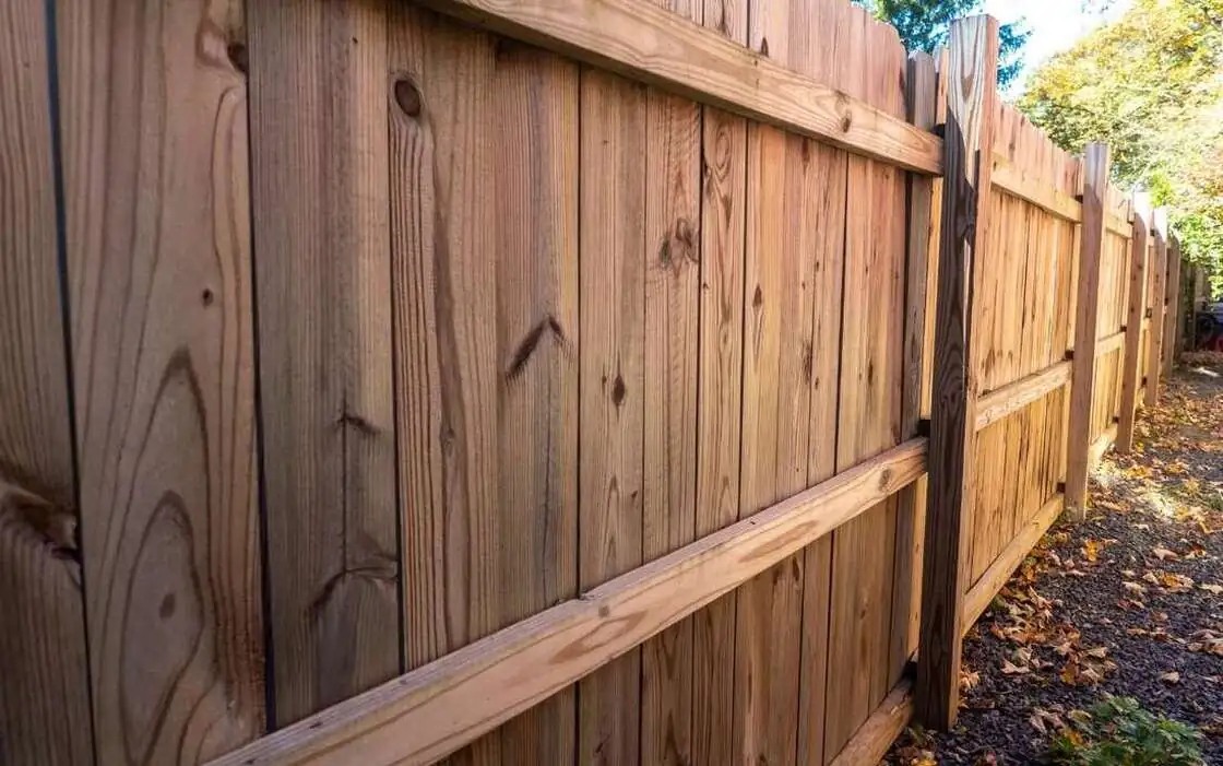 Close view of a wood privacy fence with vertical boards on horizontal rails